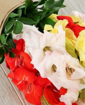 Букет с разноцветными гладиолусами в крафт бумаге